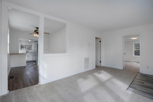 empty room with ceiling fan, plenty of natural light, and dark hardwood / wood-style floors