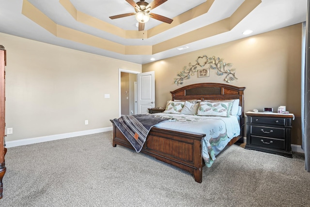 carpeted bedroom featuring ceiling fan and a raised ceiling