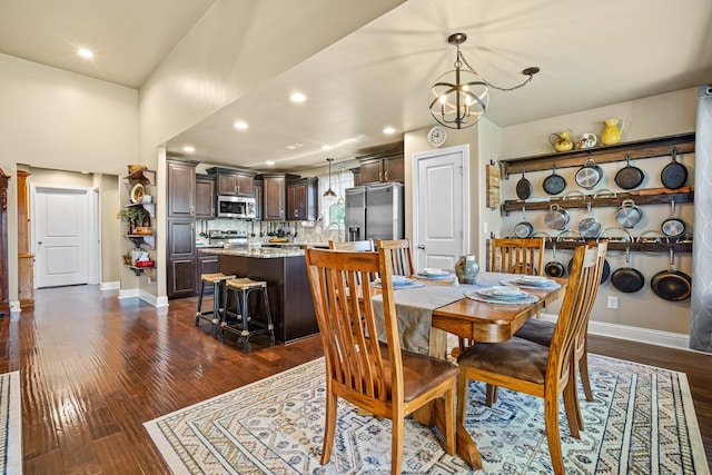 dining area featuring sink, dark wood-type flooring, and an inviting chandelier