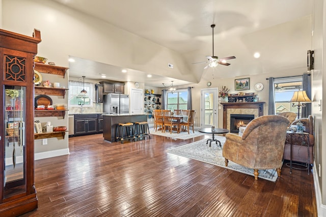 living room with high vaulted ceiling, a high end fireplace, sink, ceiling fan, and dark hardwood / wood-style flooring