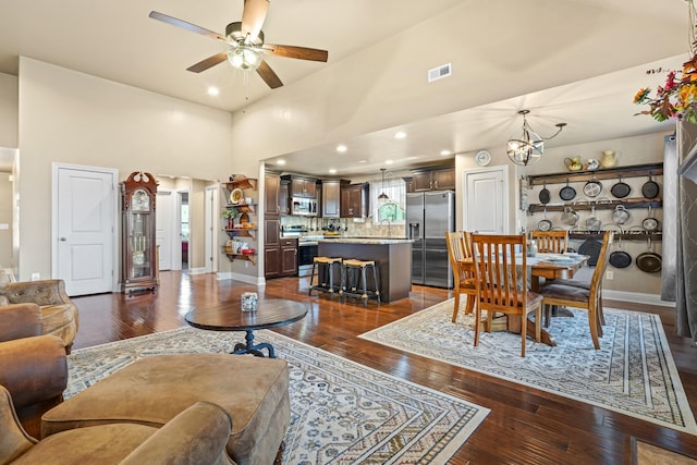 living room featuring a towering ceiling, ceiling fan with notable chandelier, dark hardwood / wood-style floors, and sink