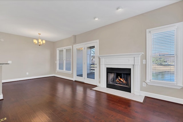 unfurnished living room with a chandelier and dark hardwood / wood-style floors