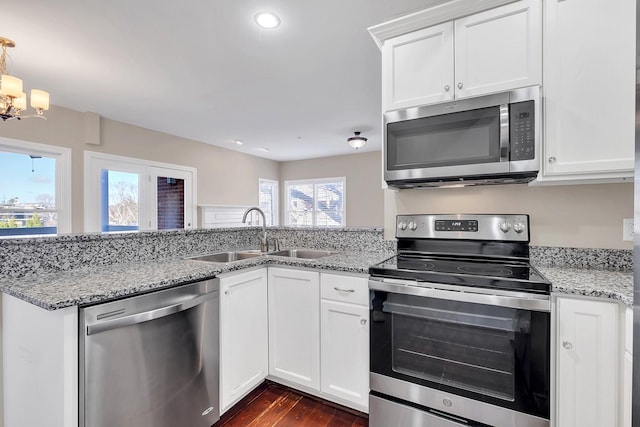 kitchen featuring light stone countertops, sink, an inviting chandelier, white cabinets, and appliances with stainless steel finishes