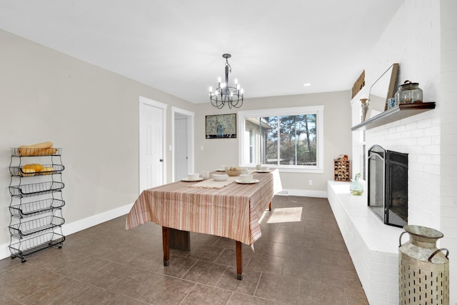 dining area featuring a fireplace, a chandelier, and dark tile patterned flooring