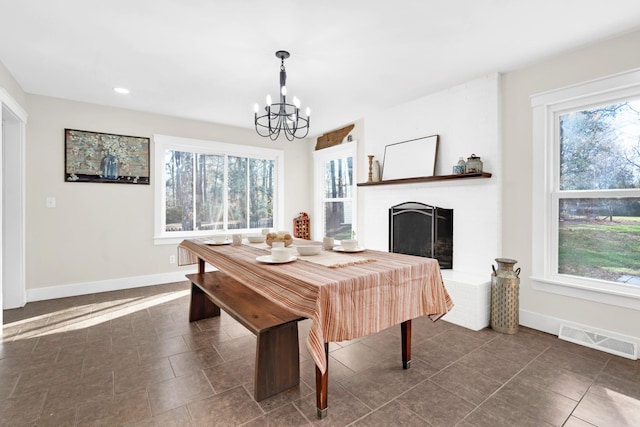 tiled dining area with a notable chandelier, plenty of natural light, and a brick fireplace