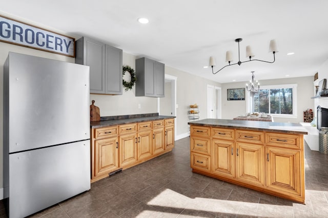 kitchen with gray cabinetry, pendant lighting, an inviting chandelier, a center island, and stainless steel refrigerator