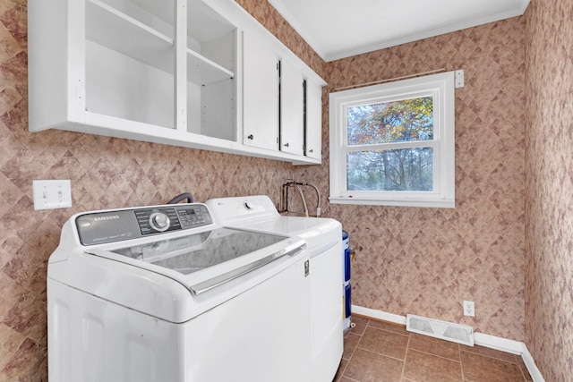 laundry room with cabinets, dark tile patterned floors, washer and clothes dryer, and ornamental molding