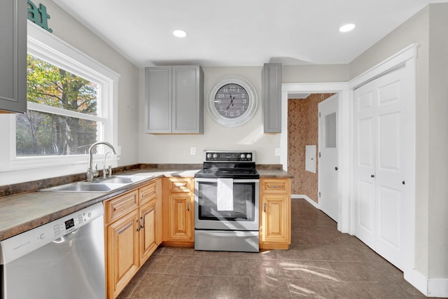 kitchen with light brown cabinetry, stainless steel appliances, dark tile patterned floors, and sink