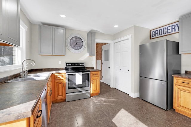 kitchen with appliances with stainless steel finishes, dark tile patterned floors, gray cabinetry, and sink