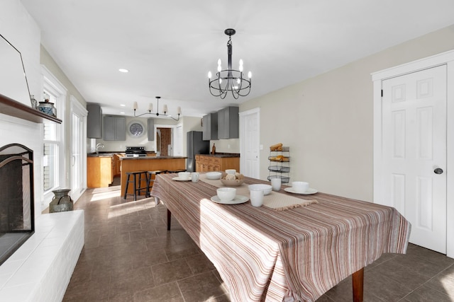 tiled dining area featuring a notable chandelier, a fireplace, and sink