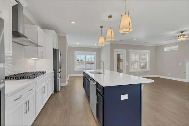 kitchen featuring white cabinetry, sink, wall chimney exhaust hood, stainless steel appliances, and hanging light fixtures