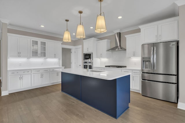 kitchen featuring stainless steel appliances, sink, wall chimney range hood, pendant lighting, and white cabinets