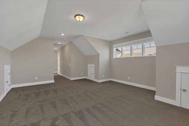 additional living space with dark carpet and vaulted ceiling