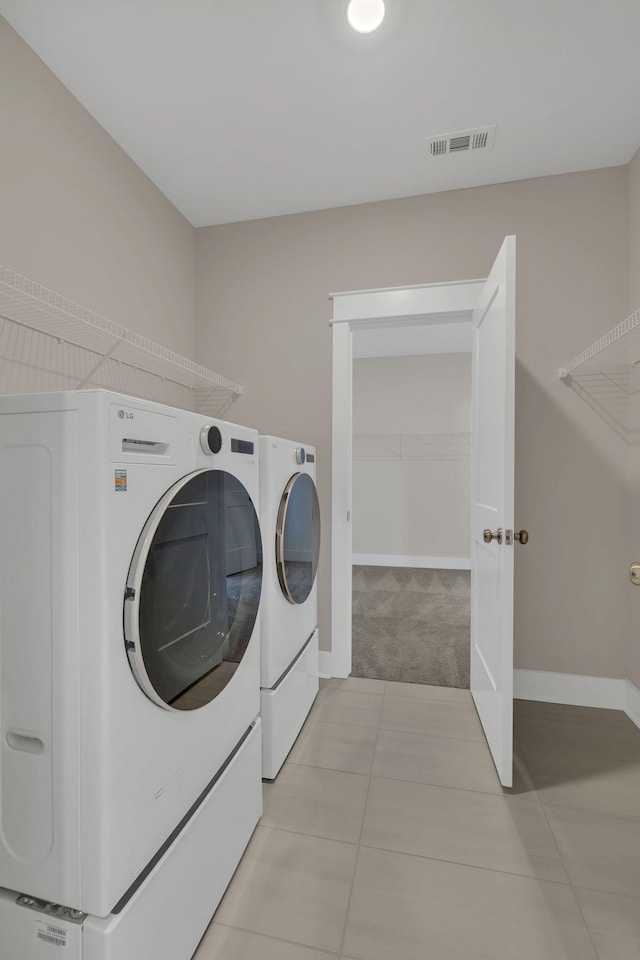 laundry area with washing machine and clothes dryer and light tile patterned floors