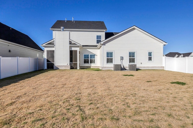 rear view of property with central AC and a yard