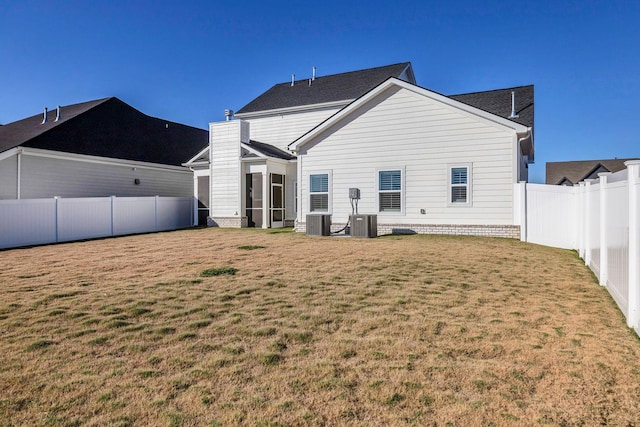 rear view of property featuring a lawn and cooling unit