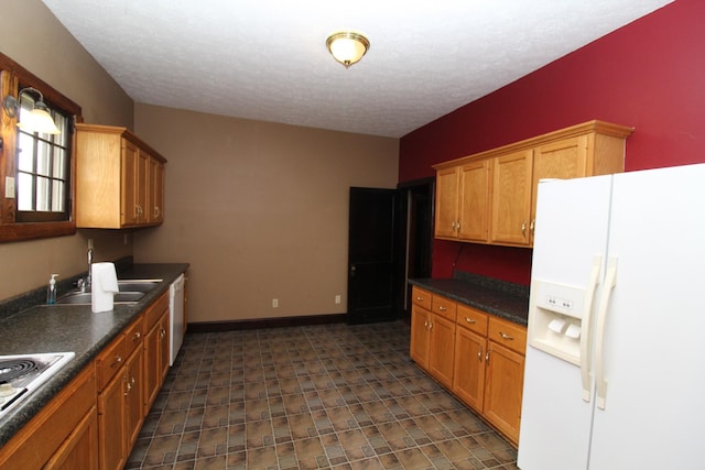 kitchen with a textured ceiling, white appliances, and sink