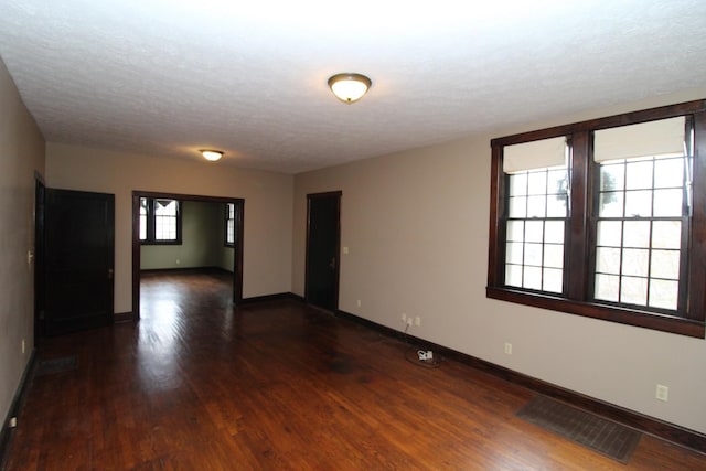 spare room featuring dark wood-type flooring and a textured ceiling