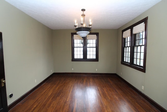 unfurnished room featuring dark hardwood / wood-style flooring, a textured ceiling, and an inviting chandelier