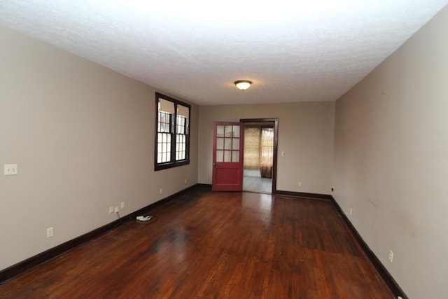 unfurnished room with a textured ceiling and dark hardwood / wood-style flooring