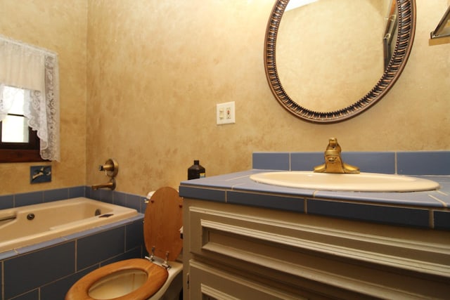 bathroom with vanity, a relaxing tiled tub, and toilet