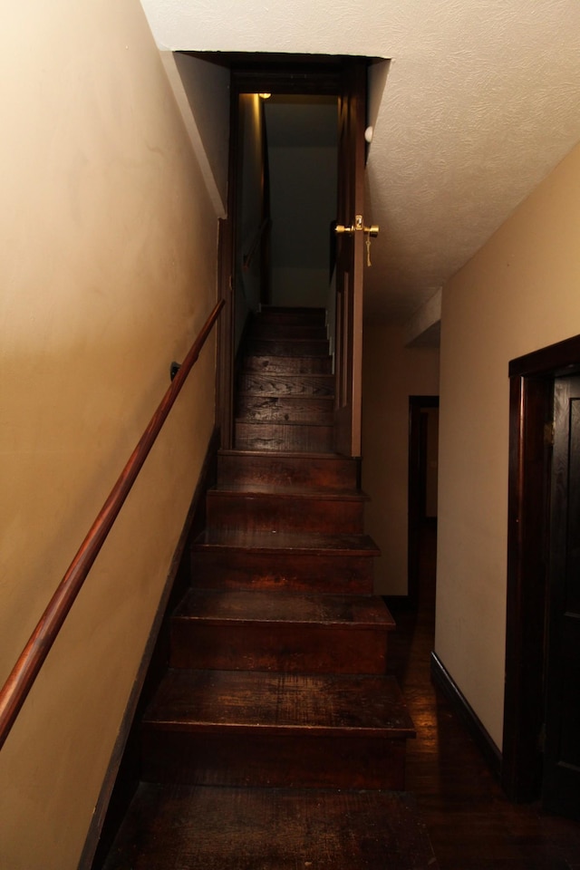 staircase with hardwood / wood-style flooring and a textured ceiling