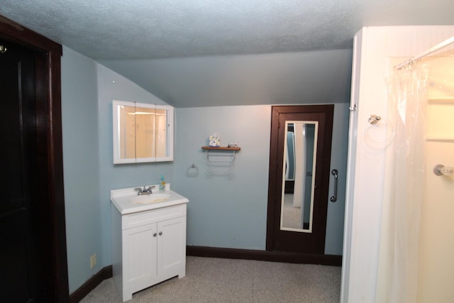 bathroom featuring vanity, a textured ceiling, and vaulted ceiling