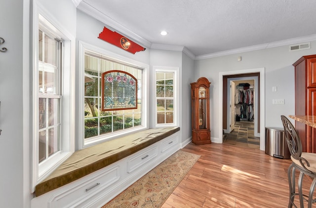 interior space with crown molding, light hardwood / wood-style flooring, and a textured ceiling