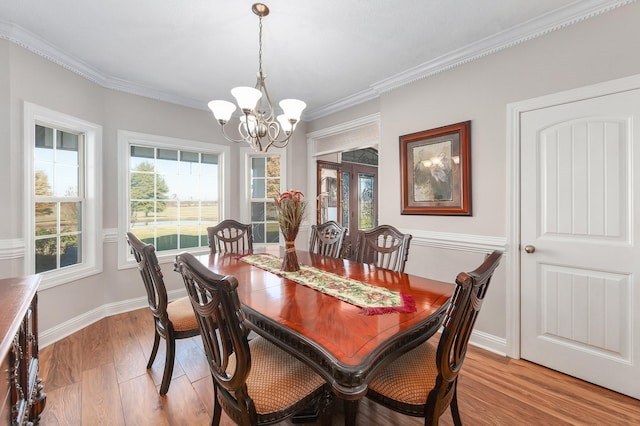 dining room with light hardwood / wood-style flooring, a notable chandelier, and ornamental molding