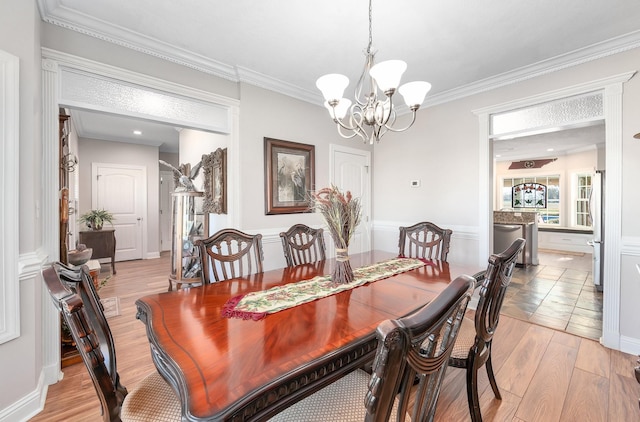 dining area featuring crown molding, light hardwood / wood-style floors, and an inviting chandelier