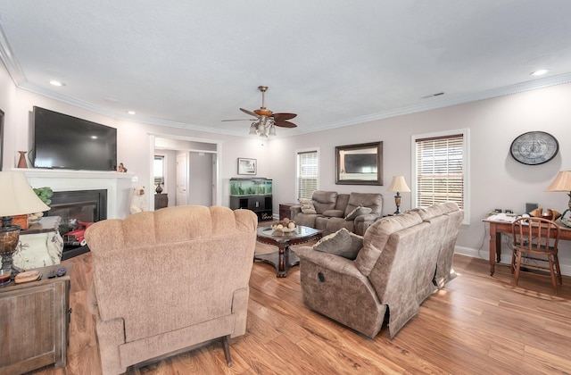 living room with light wood-type flooring, ceiling fan, and crown molding