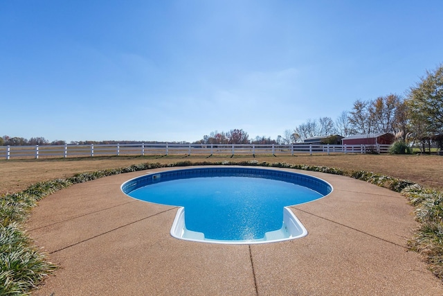 view of swimming pool with a patio area and a rural view