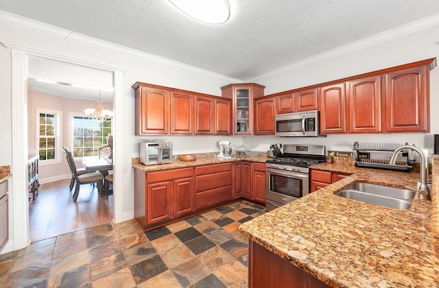 kitchen with a textured ceiling, stainless steel appliances, a notable chandelier, and sink