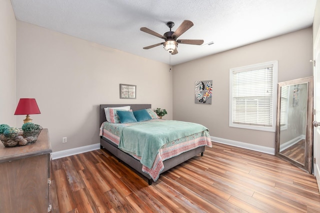 bedroom featuring ceiling fan, dark wood-type flooring, and a textured ceiling