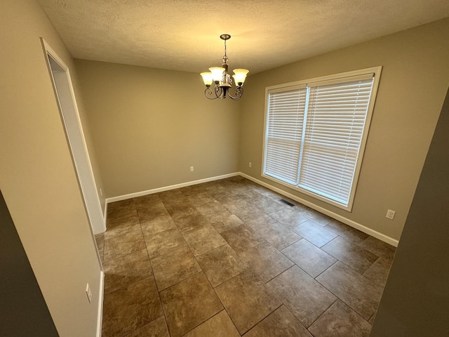 unfurnished room featuring a textured ceiling and a notable chandelier