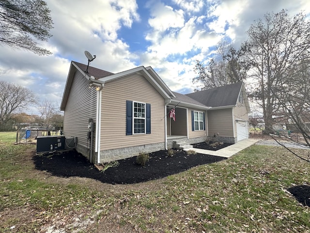 exterior space featuring a front lawn, a garage, and cooling unit