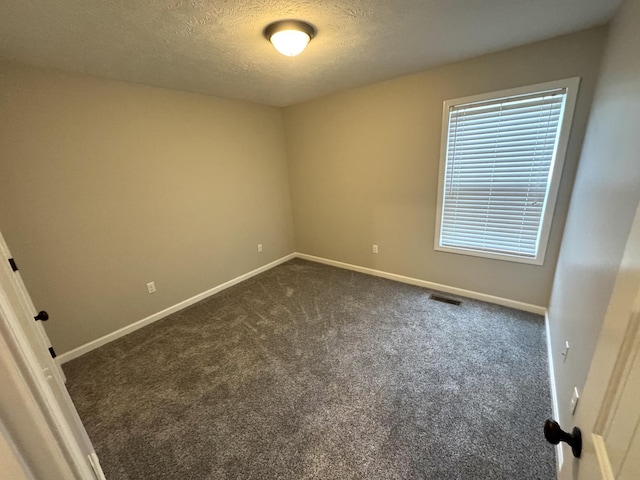 carpeted empty room featuring a textured ceiling