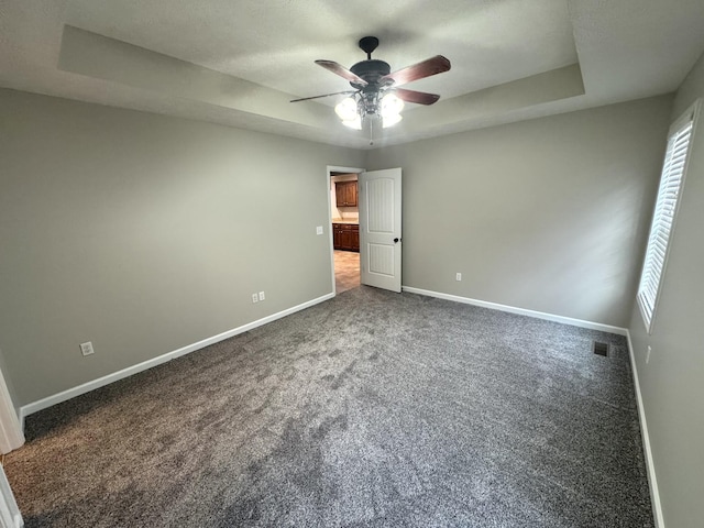 unfurnished bedroom with carpet flooring, a raised ceiling, and ceiling fan