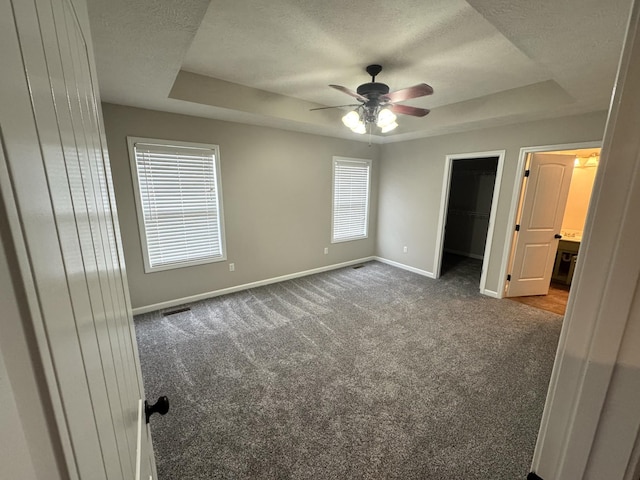 unfurnished bedroom with carpet floors, a closet, a spacious closet, and multiple windows