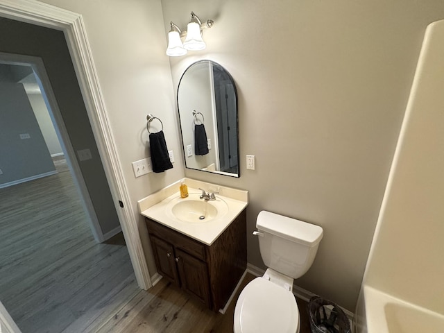 bathroom with hardwood / wood-style floors, vanity, toilet, and a tub to relax in