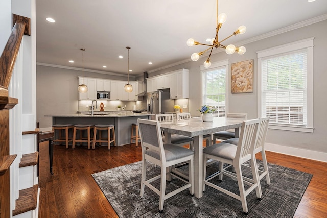 dining space featuring sink, dark hardwood / wood-style flooring, a chandelier, and ornamental molding