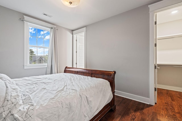 bedroom with dark hardwood / wood-style floors, a spacious closet, and a closet