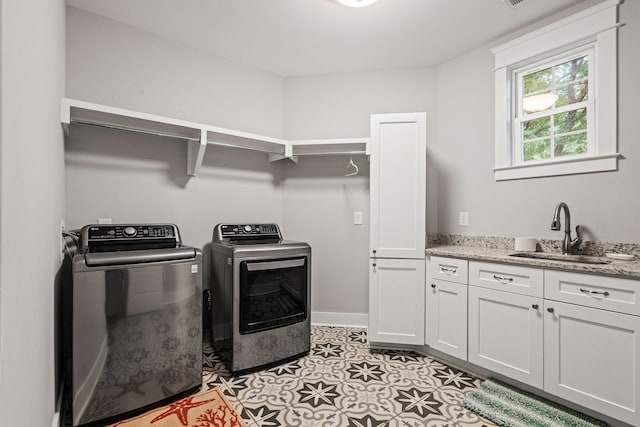 clothes washing area featuring cabinets, light tile patterned floors, washer and clothes dryer, and sink