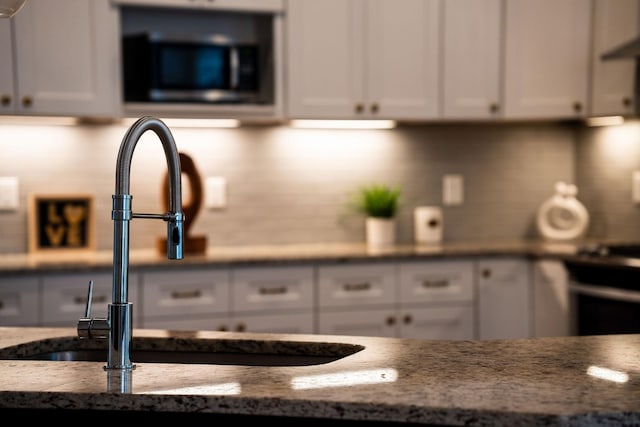 interior space featuring sink, white cabinetry, and dark stone countertops