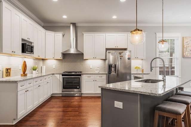 kitchen featuring light stone countertops, wall chimney exhaust hood, stainless steel appliances, white cabinetry, and hanging light fixtures