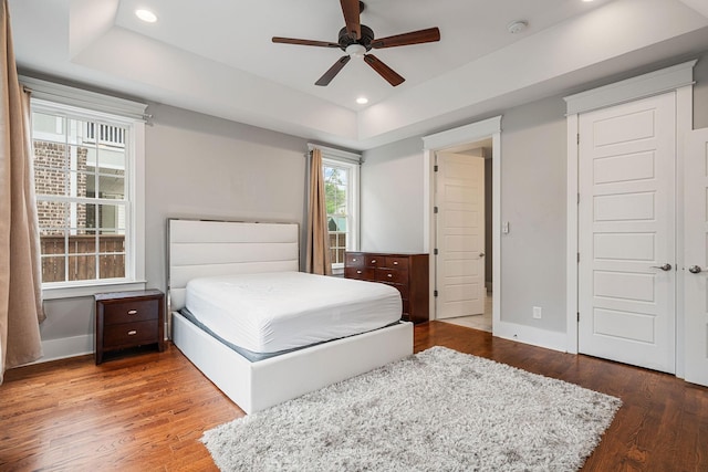 bedroom featuring a tray ceiling, ceiling fan, and wood-type flooring