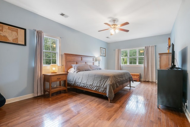 bedroom featuring wood-type flooring, multiple windows, and ceiling fan