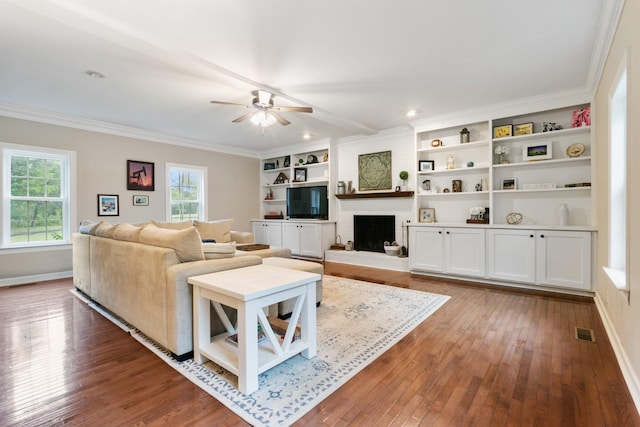 living room featuring hardwood / wood-style flooring, ceiling fan, crown molding, and a fireplace