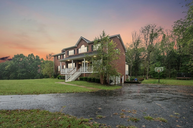 view of front of property featuring a yard, covered porch, and a trampoline