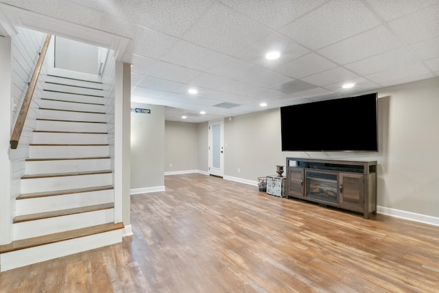 basement with a drop ceiling and light hardwood / wood-style flooring